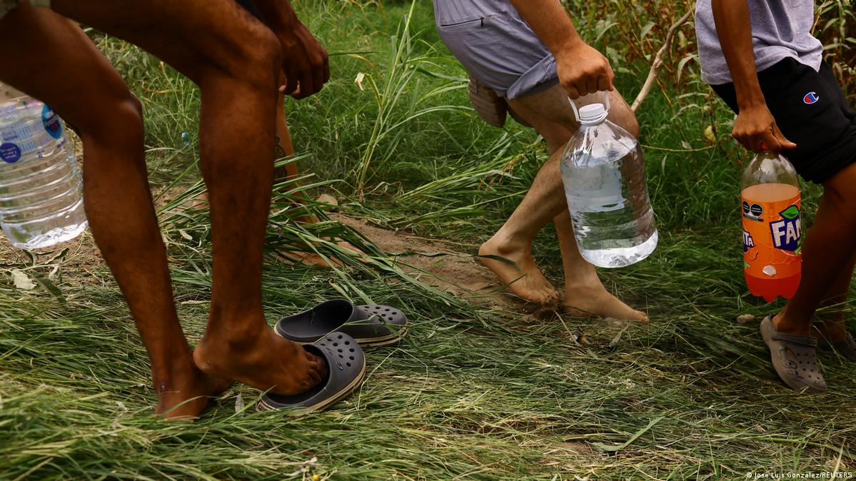 <strong>Con lo más básico</strong> En la imagen varias personas migrantes transportan bidones y botellas de agua cerca de Ciudad Juárez, México. 