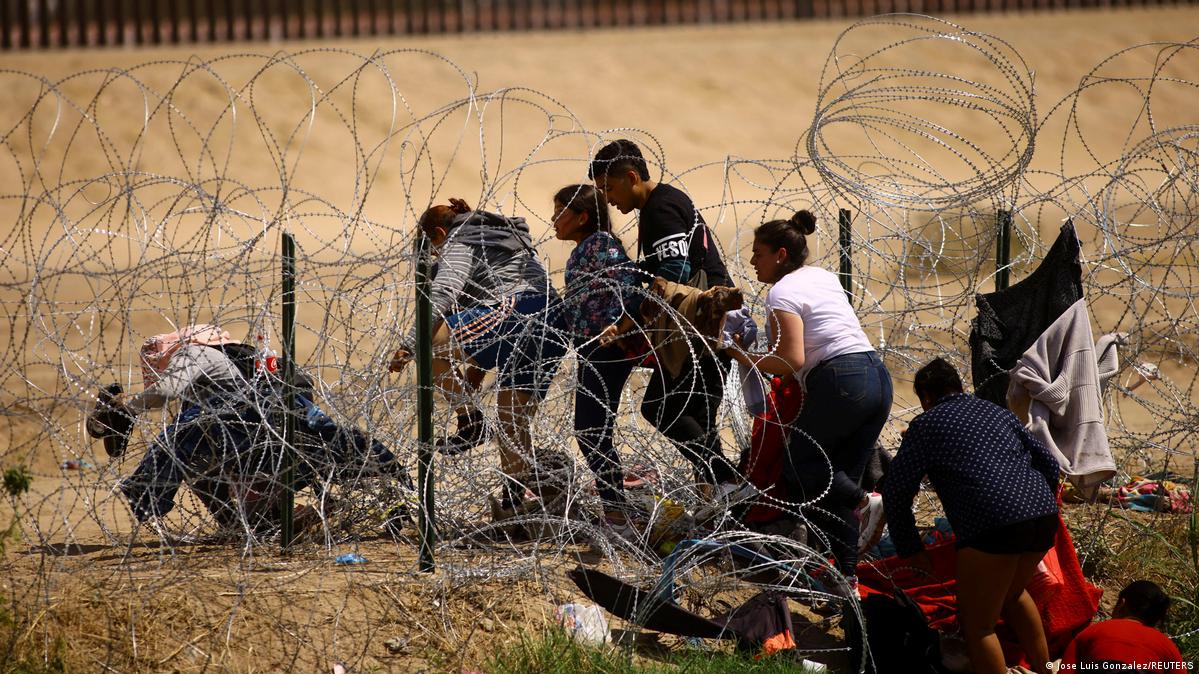Migrantes cruzan a través de una alambrada instalada en territorio mexicano a orillas del Río Bravo, según la OIM, el 2022 fue el año más mortífero para los migrantes